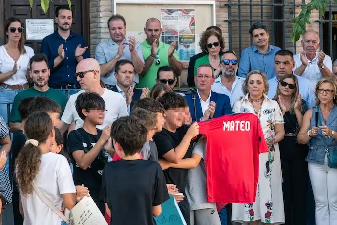 Amigos del ni&ntilde;o asesinado muestran una camiseta con su nombre, durante el minuto de silencio por el asesinato de un menor, en la puerta del Ayuntamiento de Mocej&oacute;n, a 18 de agosto de 2024, en Mocej&oacute;n, Toledo, Castilla-La Mancha (Espa&ntilde;a). El Ayuntamiento de Mocej&oacute;n ha decretado tres d&iacute;as de luto oficial por el asesinato en la ma&ntilde;ana de hoy de un menor de 11 a&ntilde;os, que se encontraba jugando al f&uacute;tbol junto a otros ni&ntilde;os de la localidad en el campo de f&uacute;tbol municipal '&Aacute;ngel Tard&iacute;o' cuando fue agredido con un objeto punzante. leer menos

Firma: Juan Moreno / Europa Press