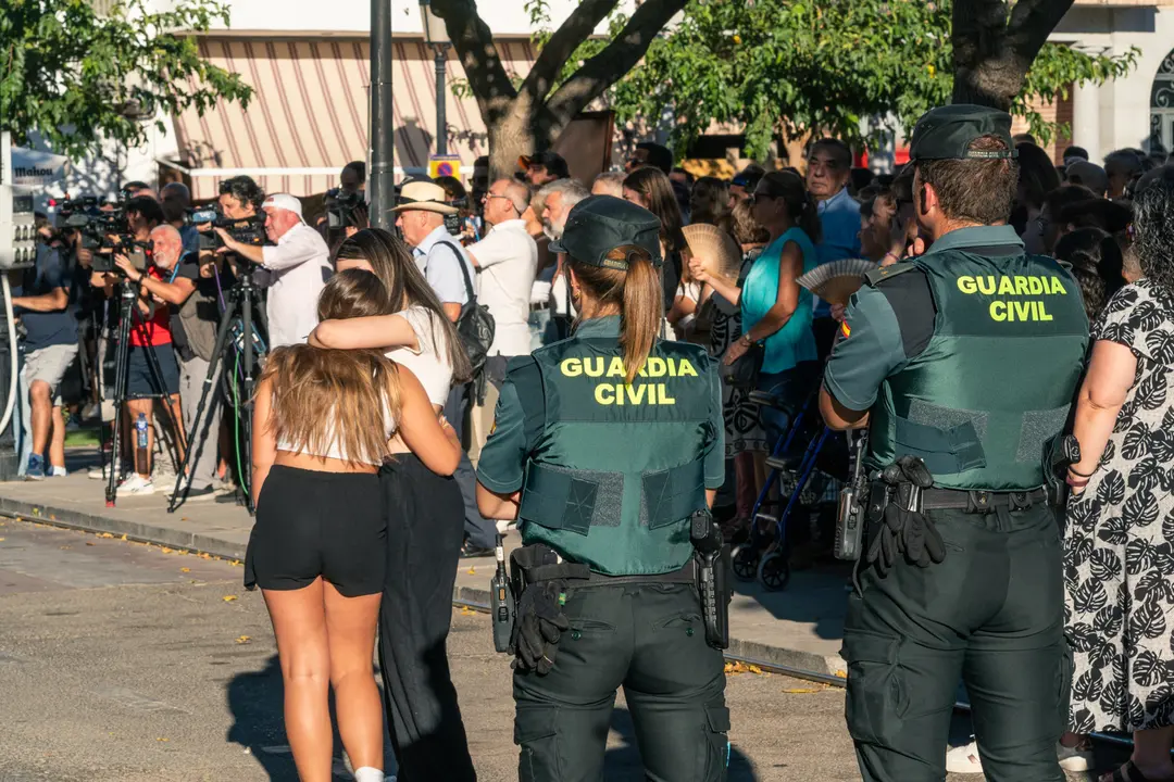 Dos agentes de la Guardia Civil observan a dos chicas abrazadas durante el minuto de silencio por el asesinato de un menor. / Juan Moreno