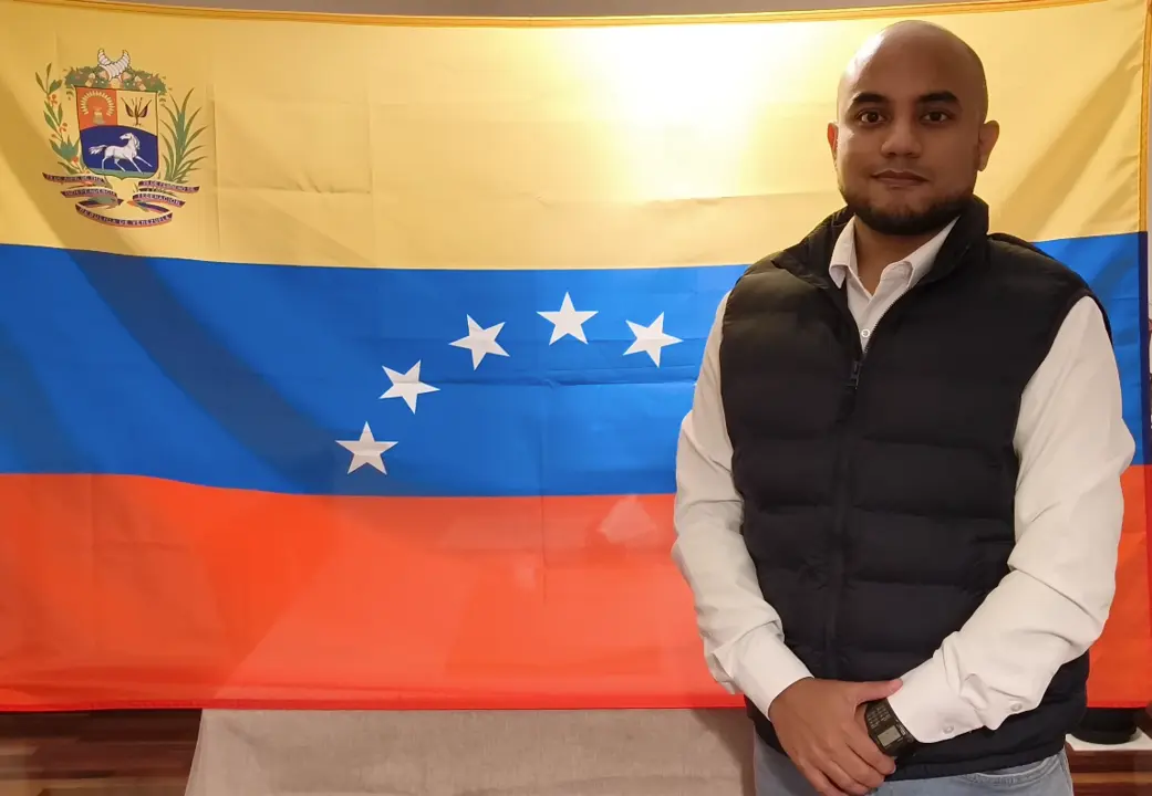 Christian Delgado, activista venezolano en Cantabria, se unir&aacute; a la manifestaci&oacute;n en Santander con la bandera de Venezuela de fondo, exigiendo el reconocimiento internacional de Edmundo Gonz&aacute;lez Urrutia como presidente leg&iacute;timo. / CD