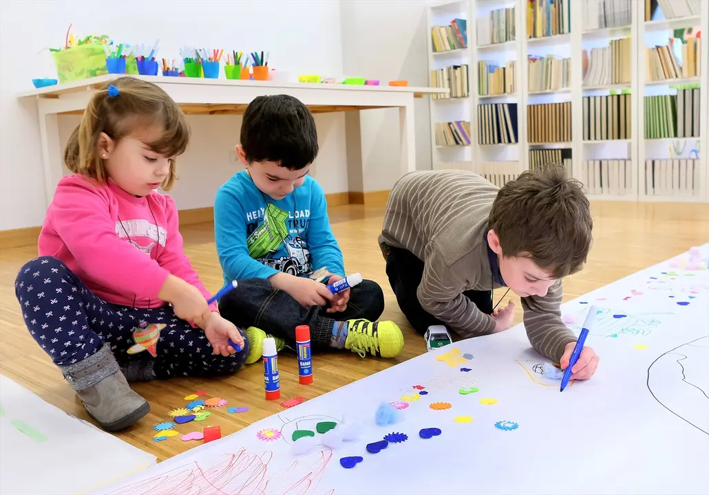 Tres ni&ntilde;os pintando en una guarder&iacute;a. / Alerta