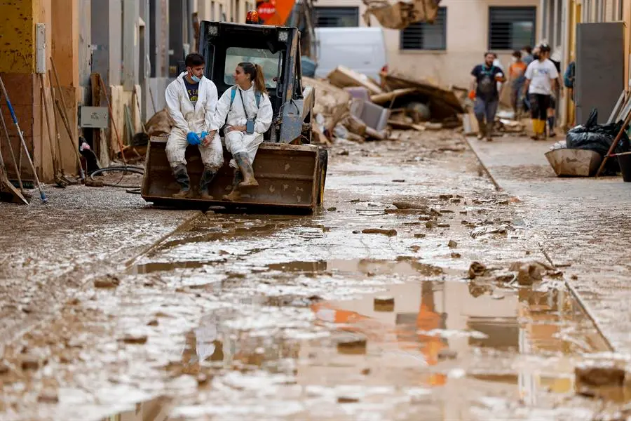 PAIPORTA (VALENCIA), 09/11/2024.- Una pareja de voluntarios se toman un descanso en una calle en Paiporta este s&aacute;bado, que afronta el fin de semana con el reto de avanzar en la recuperaci&oacute;n de la zona cero de la dana que asol&oacute; Valencia hace once d&iacute;as y de encontrar m&aacute;s personas desaparecidas, todo ello en medio de un 'ej&eacute;rcito' de voluntarios, una ingente cantidad de ayuda solidaria y el eco incesante de la pol&eacute;mica pol&iacute;tica en torno a la gesti&oacute;n de aquel fat&iacute;dico 29 de octubre.- EFE/ Jorge Zapata