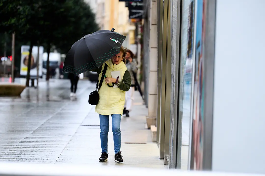 Una persona se cubre de la lluvia y el viento con paraguas. / Juanma Serrano