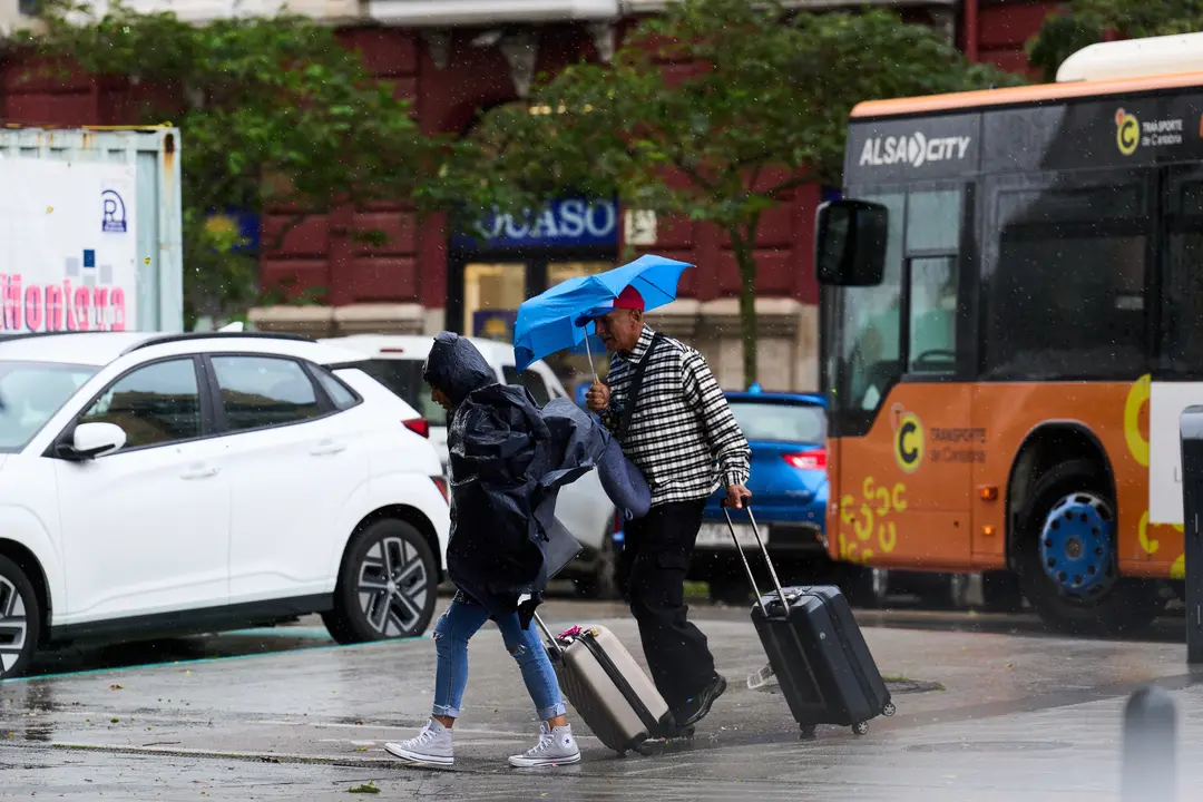 Varias personas se cubren de la lluvia y el viento con paraguas. /  Juanma Serrano