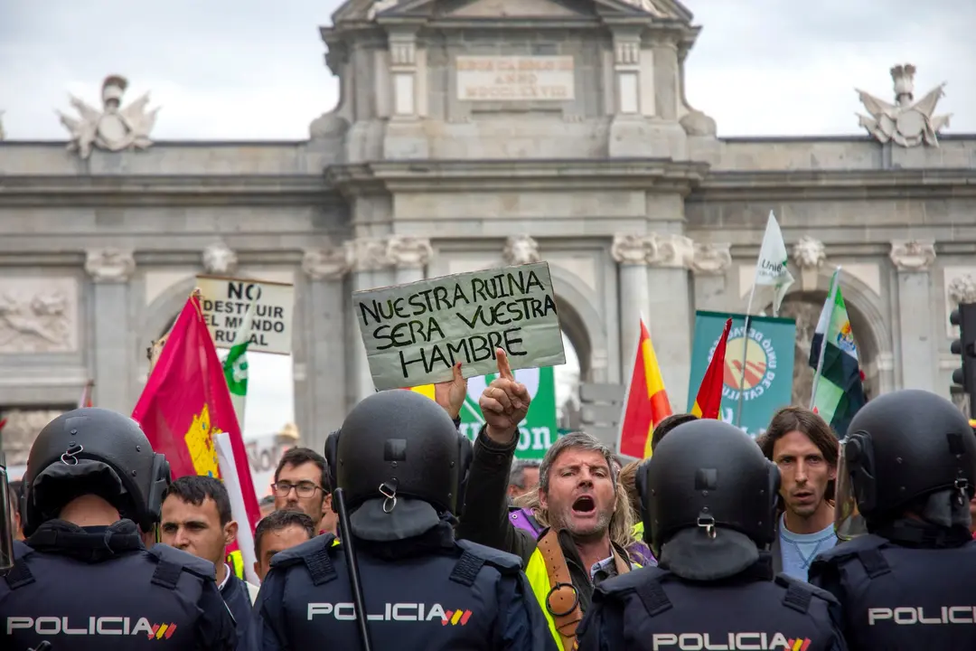 "Esta ha sido la foto elegida de Richard Zubelzu". Una captura potente que refleja la tensi&oacute;n y el clamor en las calles de Madrid durante una manifestaci&oacute;n en defensa del mundo rural. La imagen muestra a un hombre alzando un cartel con el lema "Nuestra ruina ser&aacute; vuestra hambre", mientras se enfrenta a la polic&iacute;a, en un momento de gran emotividad y protesta por la situaci&oacute;n del campo y la despoblaci&oacute;n.