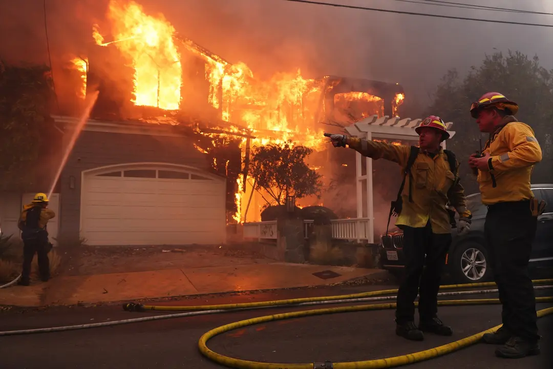 Los bomberos intentan apagar el fuego en una de las casas en Los &Aacute;ngeles. Jonathan Alcorn