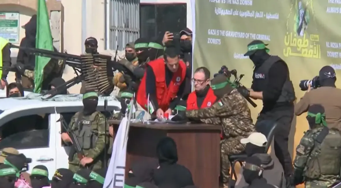 Milicianos de Ham&aacute;s junto a representantes de la Cruz Roja Internacional durante el proceso de entrega de rehenes israel&iacute;es en la Franja de Gaza. La escena, marcada por una exhibici&oacute;n militar y propagand&iacute;stica, ha generado fuertes cr&iacute;ticas por el uso pol&iacute;tico del intercambio.