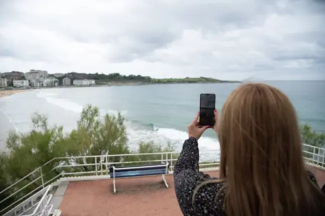Una mujer de espaldas con su m&oacute;vil enfocando al mar. / A.E.