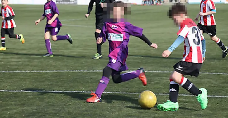 Ni&ntilde;os y ni&ntilde;as disputan un partido de f&uacute;tbol base en un ambiente de competici&oacute;n y compa&ntilde;erismo. La seguridad y el respeto en el deporte infantil son fundamentales para su desarrollo.