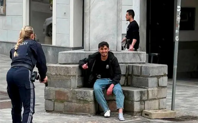 Momento de la detenci&oacute;n: agentes de polic&iacute;a apuntan con sus armas a un hombre sentado en una fuente, instantes antes de su arresto en Villach, Austria