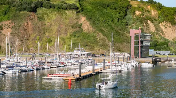 Velero entrando al puerto deportivo de Laredo con el edificio de la Marina al fondo y la monta&ntilde;a de la Atalaya. / A.S.