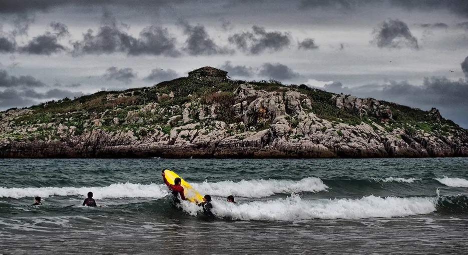 Vista de unos surfistas con la isla de San Pedruco en el fondo. / A.N.