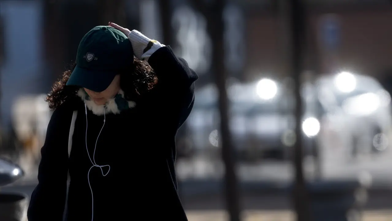 Una mujer abrigada con bufanda y gorro pasea por Madrid. / Eduardo Parra