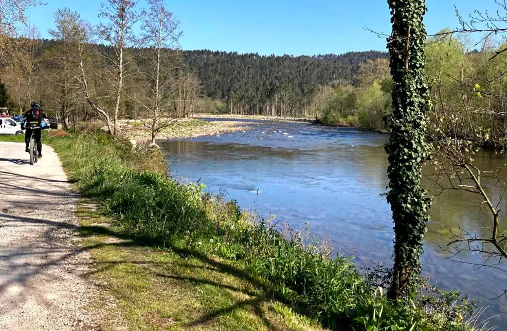 Una persona andando en bici al lado del r&iacute;o Saja en Cabrojo. / A.C.