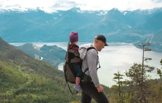 Un padre y su hijo disfrutan de una caminata en la monta&ntilde;a, simbolizando el v&iacute;nculo, la protecci&oacute;n y el acompa&ntilde;amiento que representa la paternidad.