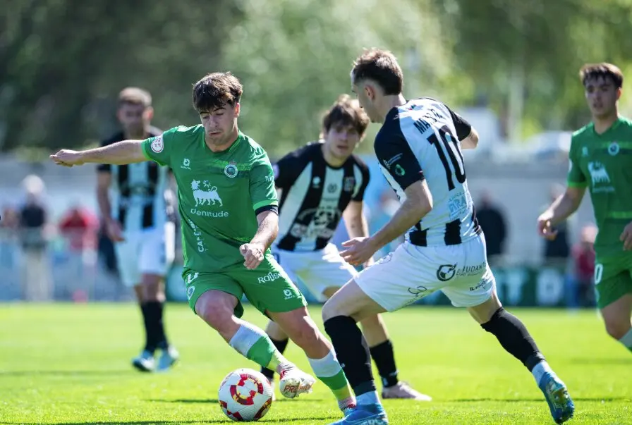 Un jugador del Rayo Cantabria protege el bal&oacute;n ante la presi&oacute;n de un rival del Escobedo durante el intenso derbi c&aacute;ntabro disputado en La Planchada.