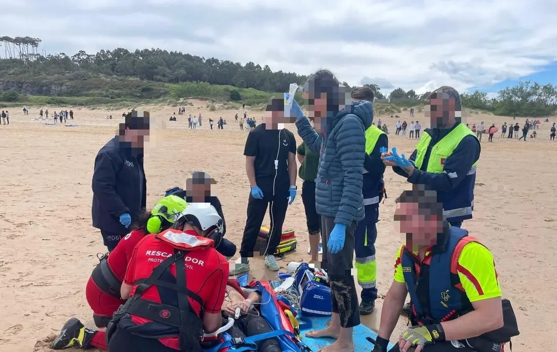 Sanitarios y rescatadores atienden en la playa de Somo a un hombre de unos 60 a&ntilde;os en estado muy grave tras ser sacado del agua por surfistas. / 112 Cantabria