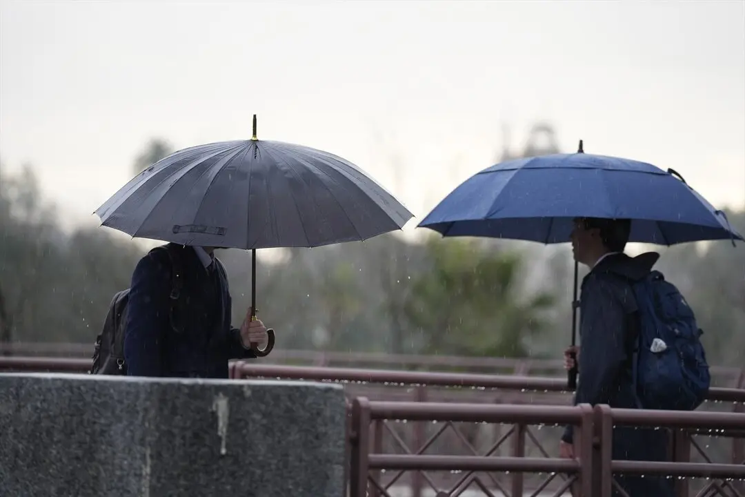 Varias personas se protegen de la lluvia con un paraguas. / Joaquin Corchero