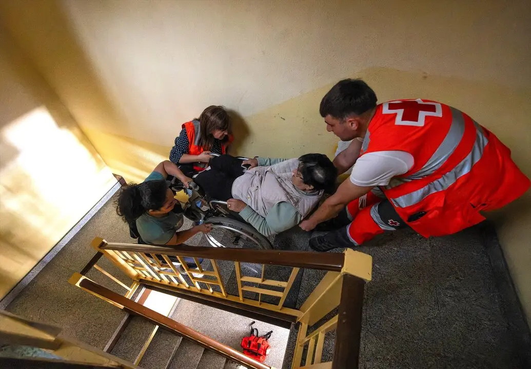 Efectivos de emergencias ayudan a una mujer a subir las escaleras durante el apag&oacute;n. / Tom&aacute;s Alonso