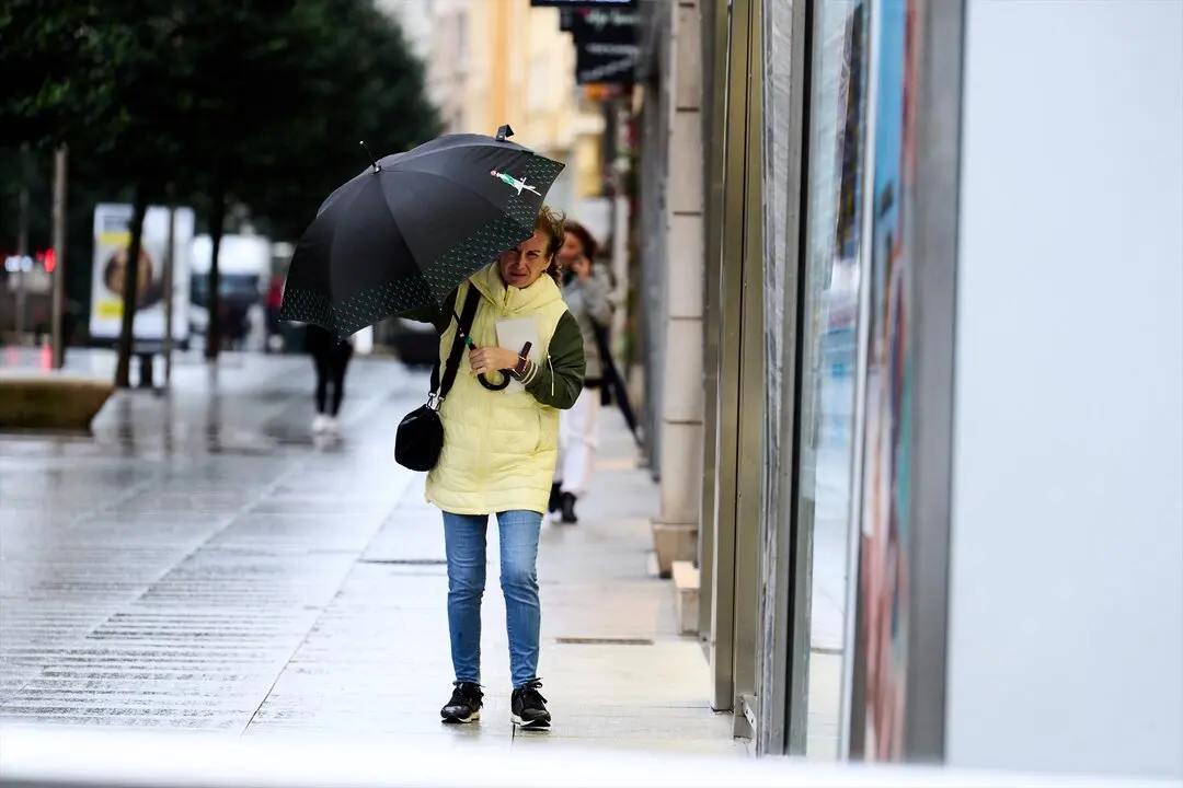 Una persona se cubre de la lluvia y el viento con paraguas. / Juanma Serrano