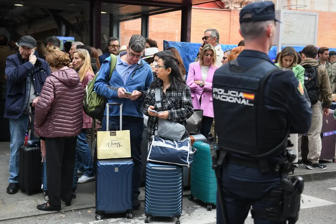 Un agente de Polic&iacute;a Nacional frente a varias personas en la estaci&oacute;n de Atocha. / EP