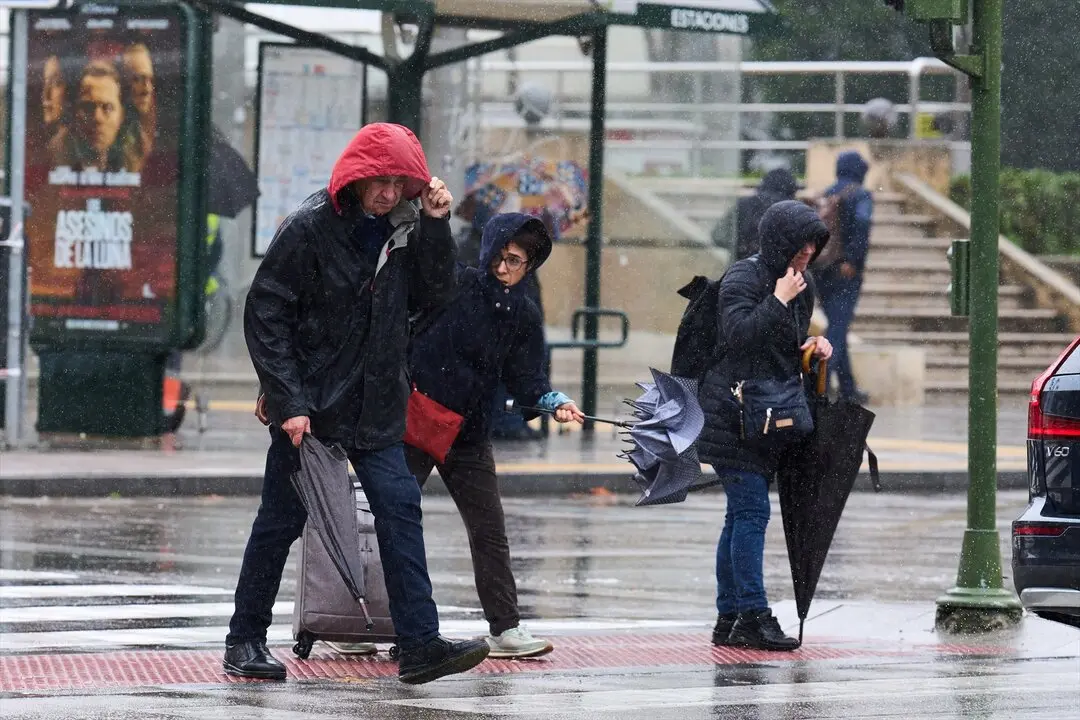 Varias personas tratan de cubrirse de la lluvia y el viento. / Juanma Serrano