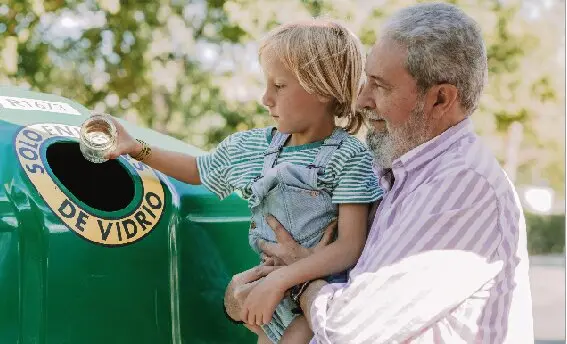 Un ni&ntilde;o junto a su abuelo tirando un tarro de vidrio en el contenedor de vidrio. / ALERTA