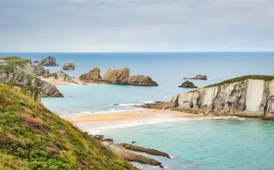 T&oacute;mbolo de arena que une la isla del Castro con la costa quebrada de Cantabria durante la marea baja. / A.S.