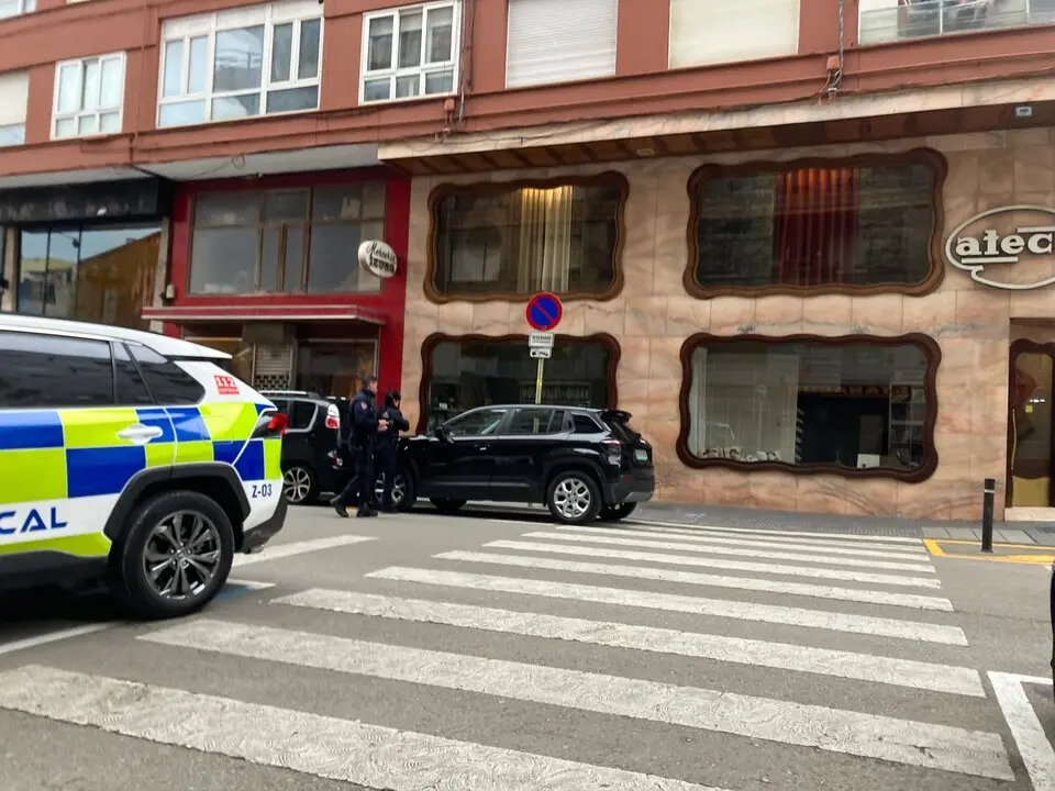 Dos polic&iacute;as locales de Torrelavega se disponen a sancionar a un veh&iacute;culo estacionado, dejando la multa en el parabrisas, en el &aacute;rea prevista para la futura Zona de Bajas Emisiones.