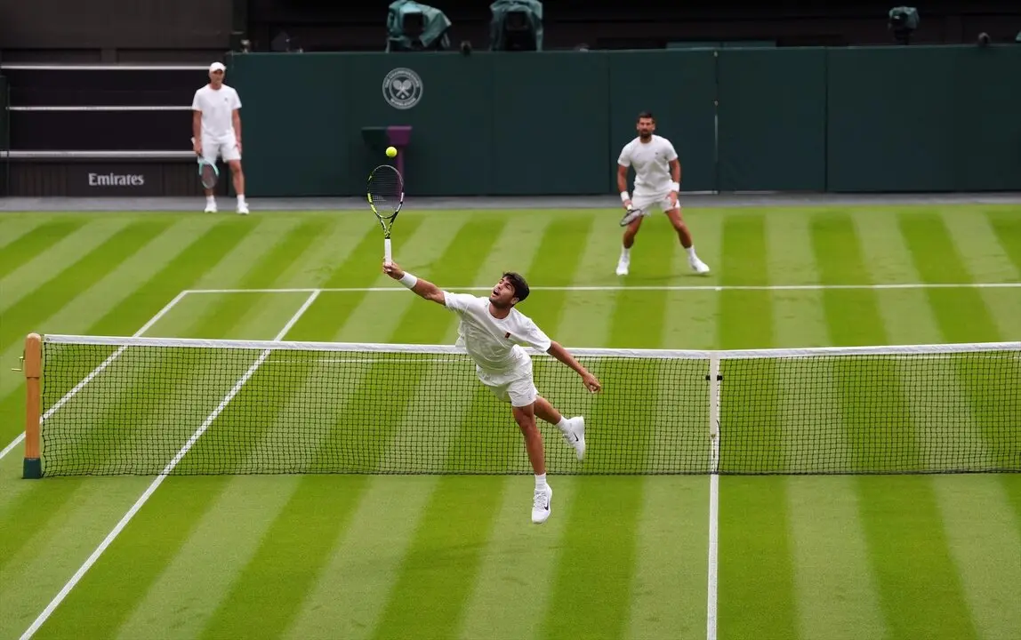 El tenista espa&ntilde;ol Carlos Alcaraz devuelve un rev&eacute;s al serbio Novak Djokovic durante un entrenamiento antes de Wimbledon. / Ben Whitley
