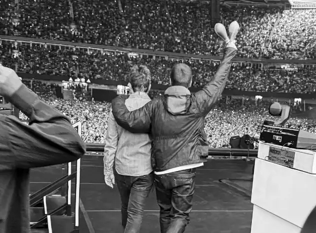 Liam abraza a Noel Gallagher al comienzo del concierto de Oasis. / Oasis