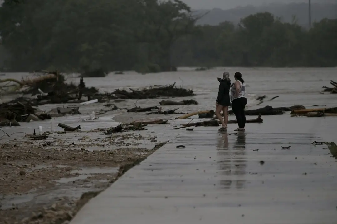 Dos empleados observan el &aacute;rea donde docenas de remolques fueron arrastrados por la crecida de las aguas en el r&iacute;o Guadalupe en Ingram, Texas. / EP