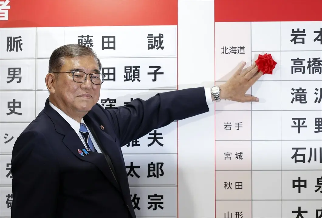 El primer ministro japon&eacute;s y presidente del gobernante Partido Liberal Democr&aacute;tico (PLD), Shigeru Ishiba, coloca una rosa roja de papel sobre el nombre de un candidato electo en la sede del PLD. / EP