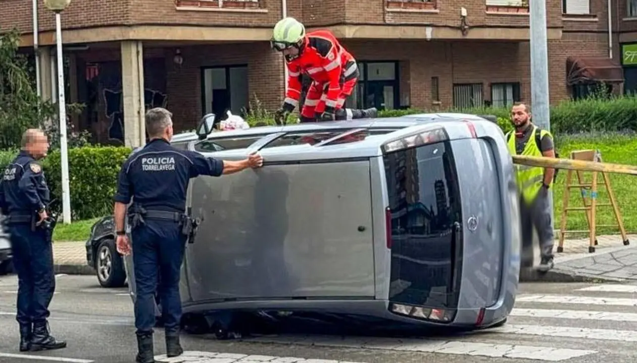 Polic&iacute;as tratan de rescatar a la conductora del veh&iacute;culo volcado, este martes, en El Zapat&oacute;n (Torrelavega).
