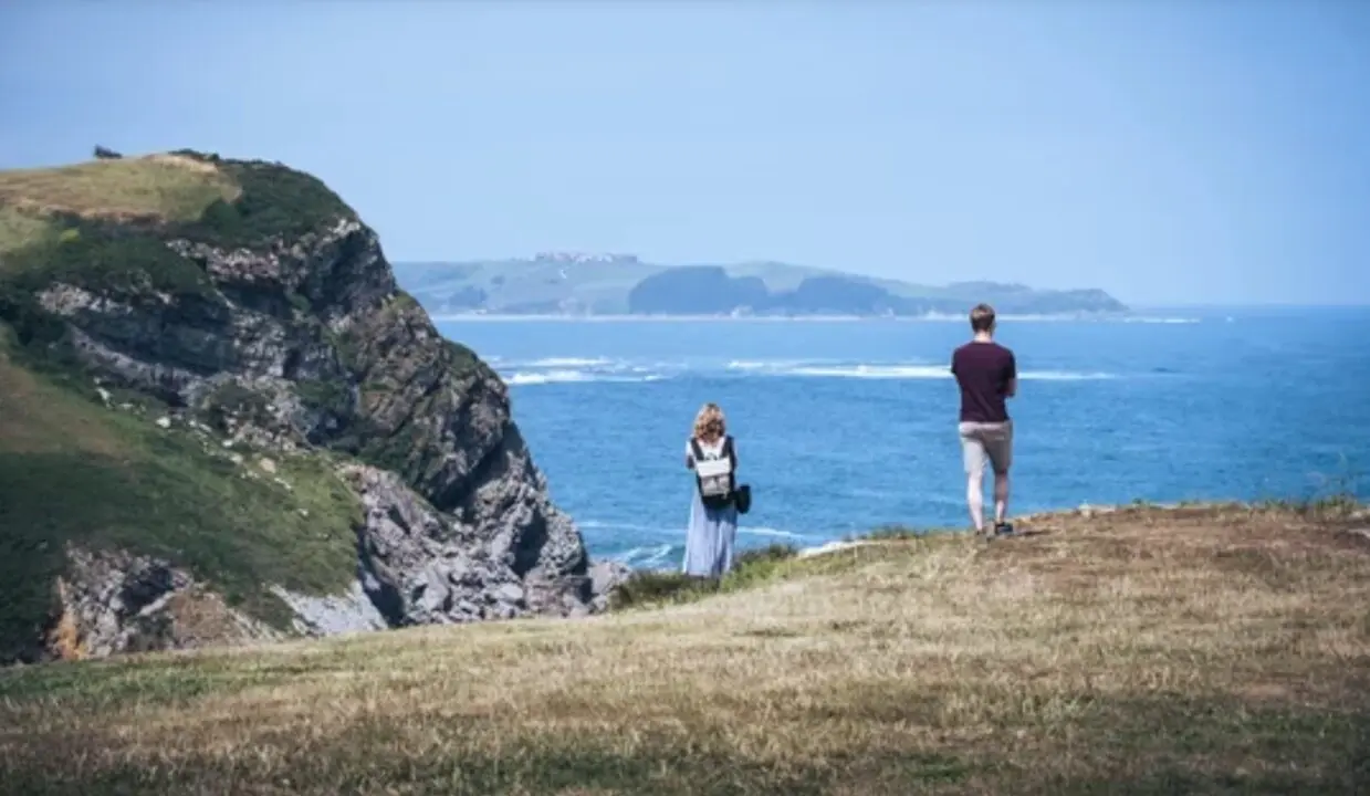 Dos turistas contemplan el mar Cant&aacute;brico desde un acantilado en la costa norte de Espa&ntilde;a, un destino cada vez m&aacute;s elegido por viajeros que buscan paisajes naturales, tranquilidad y temperaturas suaves durante el verano.