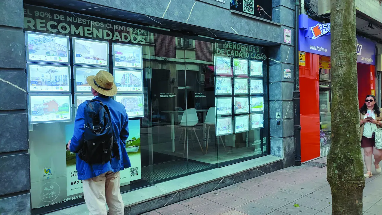 Un hombre observa el escaparate de una inmobiliaria, donde se anuncian pisos en venta y alquiler. / Alerta
