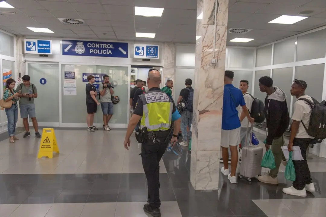 Un grupo de personas hacen cola en el Puerto de Ceuta, antes de ser trasladados a la pen&iacute;nsula. / Antonio Sempere