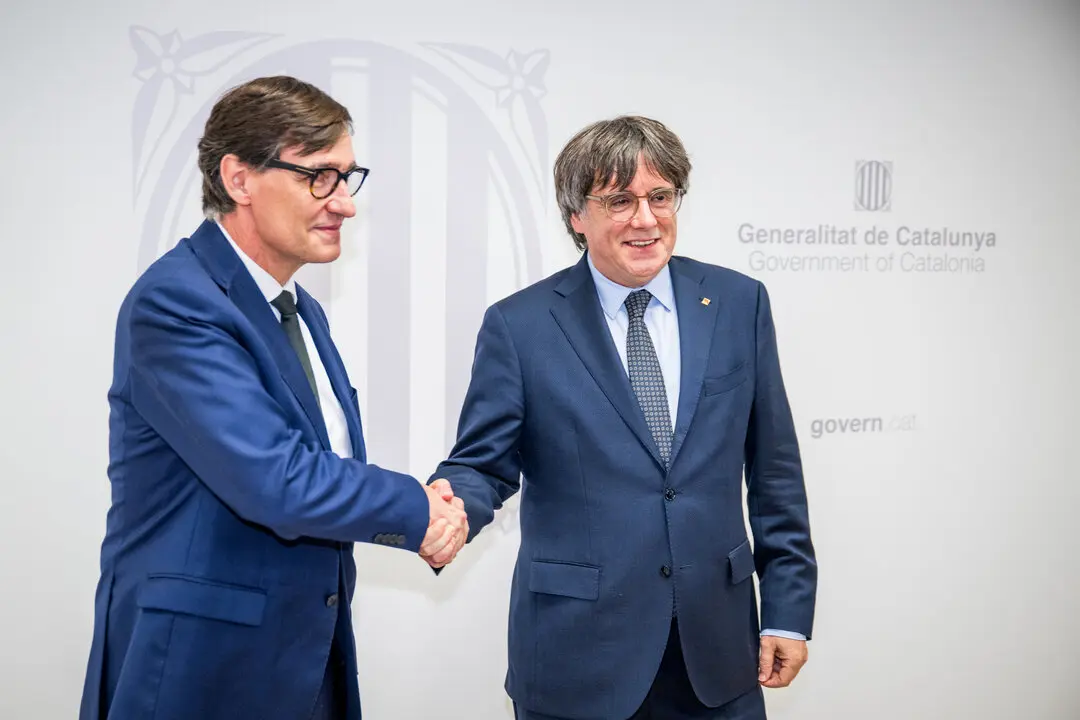 El presidente de la Generalitat, Salvador Illa (i), saluda al presidente de Junts per Catalunya, Carles Puigdemont. / EP