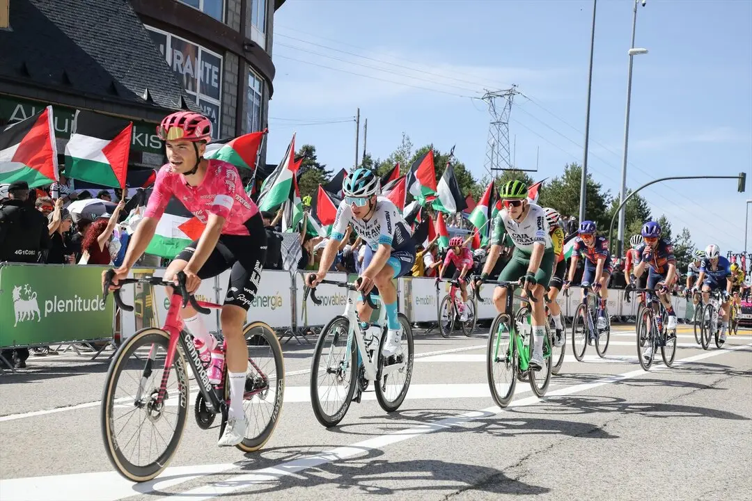 Varios ciclistas pasan por una zona con protestas propalestinas durante la 20&ordf; etapa de la Vuelta Ciclista a Espa&ntilde;a. / Rafael Bastante