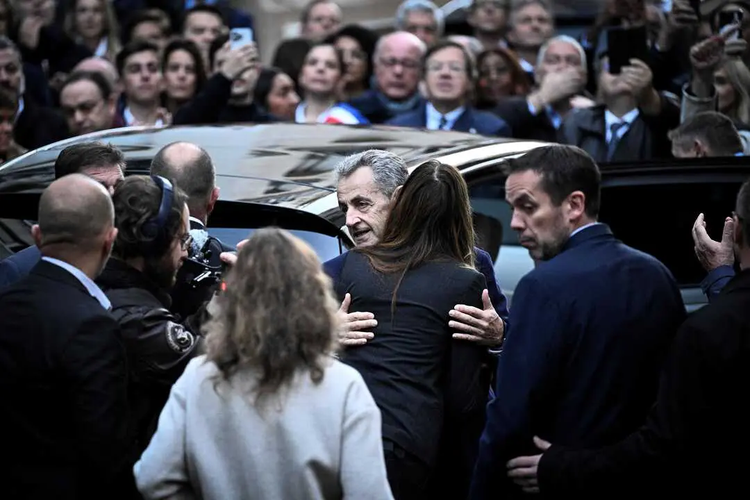 El expresidente franc&eacute;s Nicolas Sarkozy (C) abraza a su esposa Carla Bruni-Sarkozy al salir de su residencia para presentarse en la prisi&oacute;n de La Sante. / EP