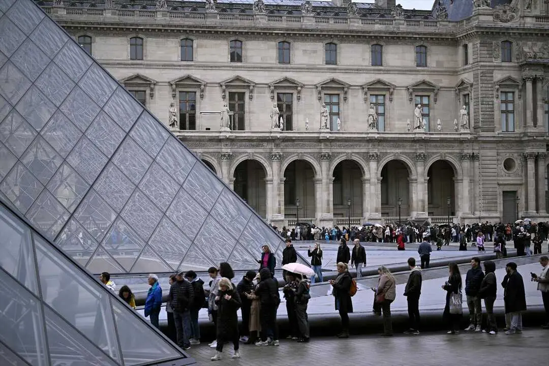 La gente hace cola en el patio de la Pir&aacute;mide del Louvre. / Julien De Rosa