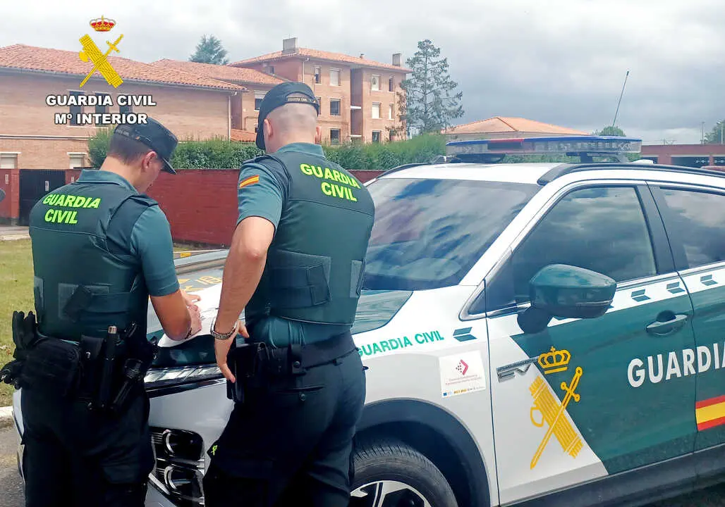 Dos guardias civiles junto al coche patrulla. / G.C.