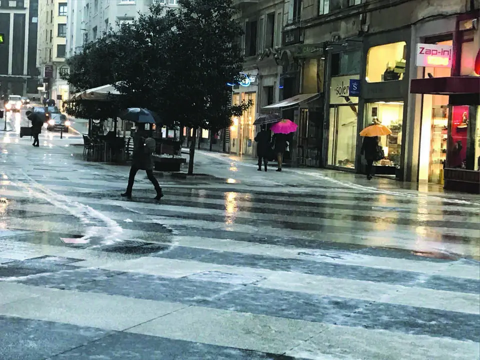 Varias personas con paraguas pasean bajo la lluvia en el centro de Santander. / alerta