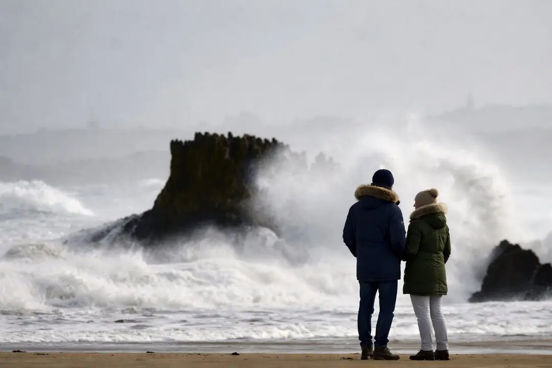 Una pareja contempla el bravo oleaje del mar Cant&aacute;brico en Santander, mientras las olas rompen con fuerza contra las rocas en un d&iacute;a de temporal invernal. / ALERTA