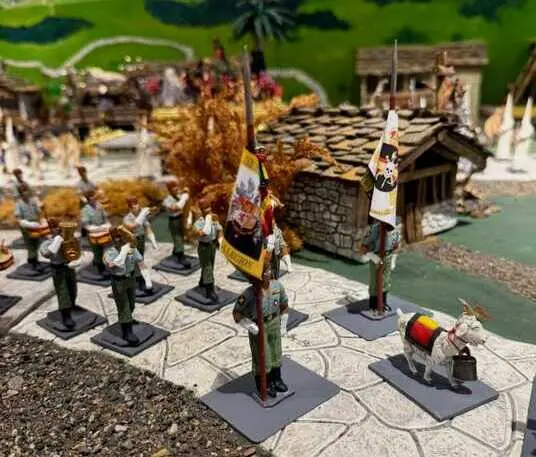 Detalle de la exposici&oacute;n Miniatura, donde figuras procesionales en peque&ntilde;o formato &mdash;con estandartes, banda y escena rural c&aacute;ntabra al fondo&mdash; recrean la est&eacute;tica de la Semana Santa del sur en un entorno pasiego &uacute;nico en Espa&ntilde;a. / A.E