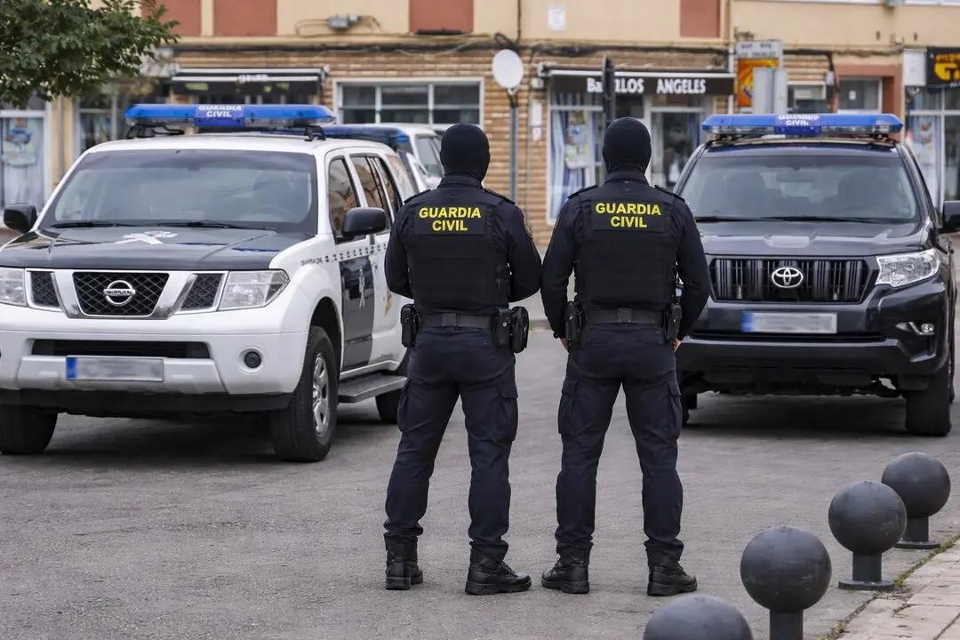 Dos agentes de la Guardia Civil junto a veh&iacute;culos oficiales durante el operativo desplegado en Cantabria que se ha saldado con doce detenidos por tr&aacute;fico de drogas.