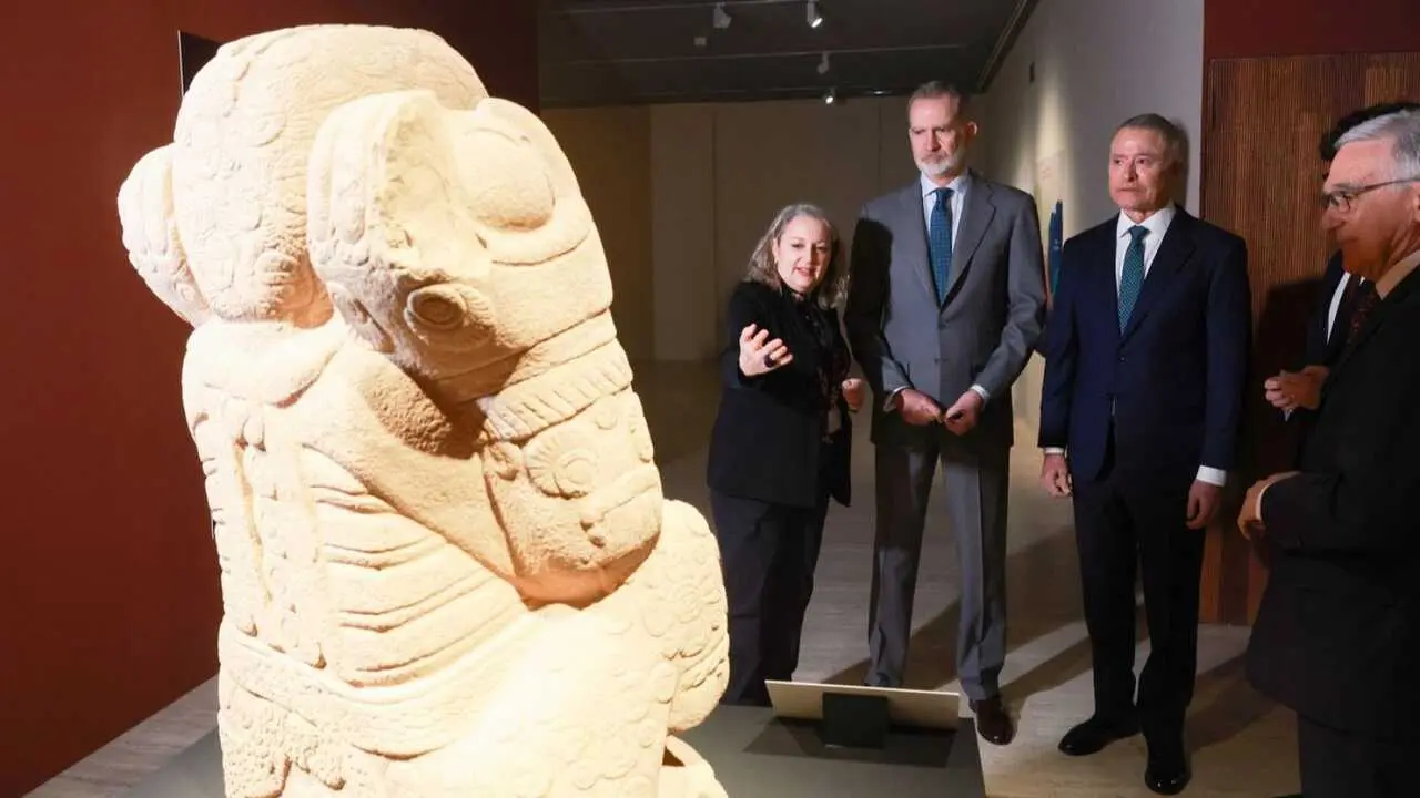 Un grupo de autoridades atiende las explicaciones de una gu&iacute;a ante una escultura prehisp&aacute;nica durante una visita institucional a la exposici&oacute;n.