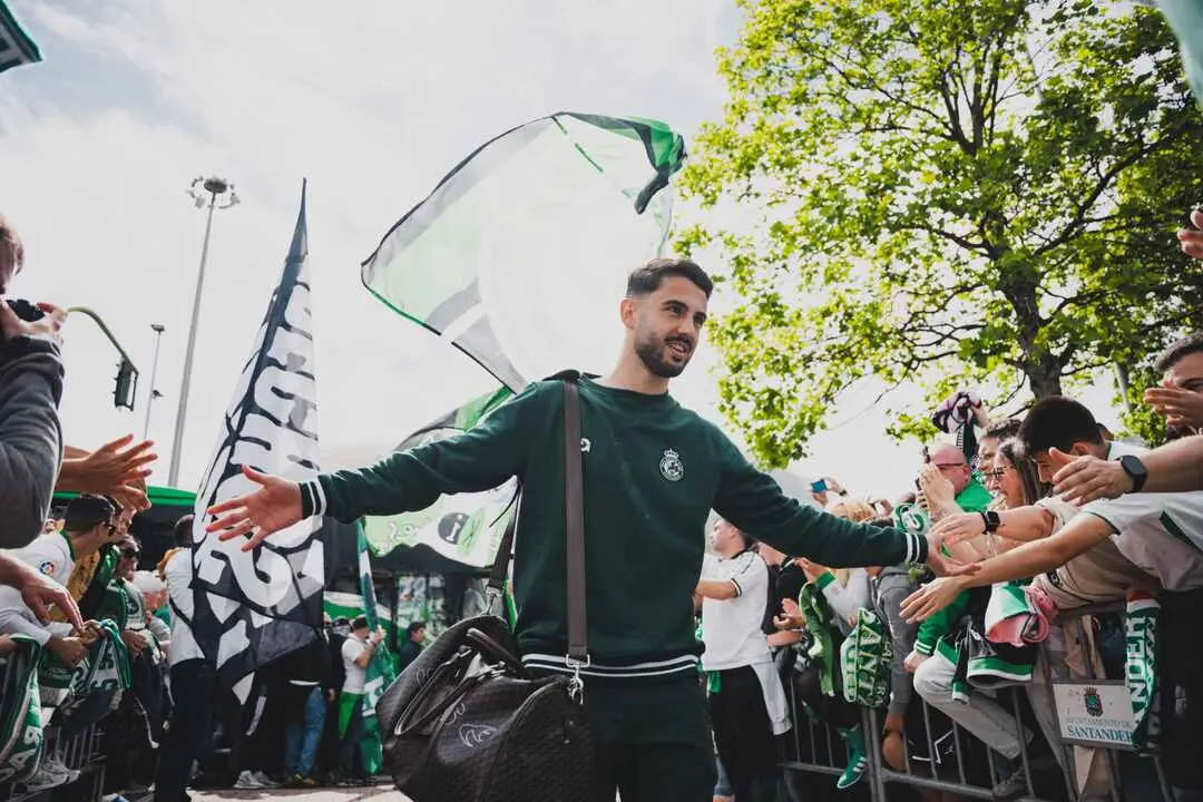 Un jugador del Racing saluda a la afici&oacute;n a su llegada a El Sardinero en medio de un recibimiento espectacular marcado por las banderas, los c&aacute;nticos y la ilusi&oacute;n del racinguismo.
