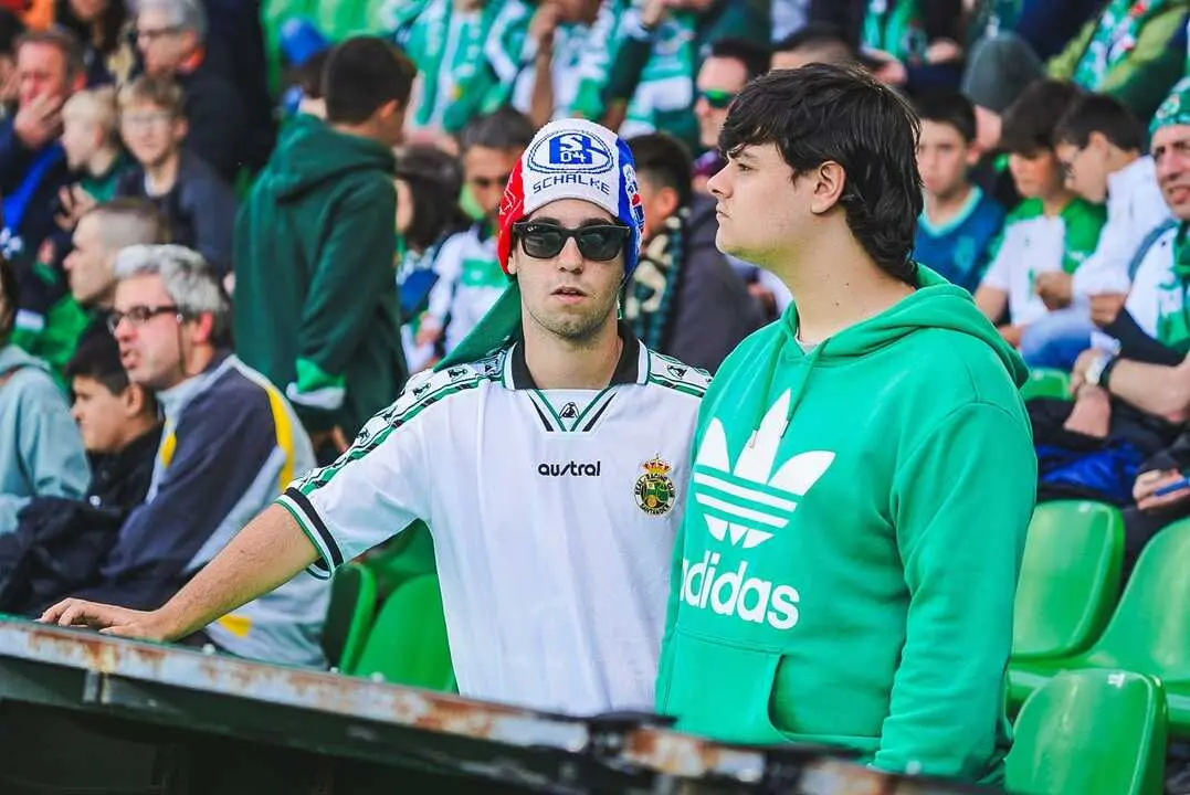 Dos aficionados del Racing esperan el inicio del partido en El Sardinero, uno de ellos con un llamativo gorro del Schalke 04 en una grada completamente entregada a la ilusi&oacute;n del ascenso.