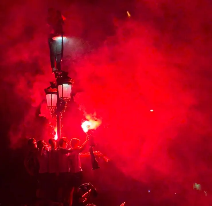 Las bengalas ti&ntilde;en de rojo la madrugada santanderina mientras cientos de racinguistas celebran el ascenso en una noche hist&oacute;rica que convirti&oacute; las calles de la ciudad en una aut&eacute;ntica locura verdiblanca.