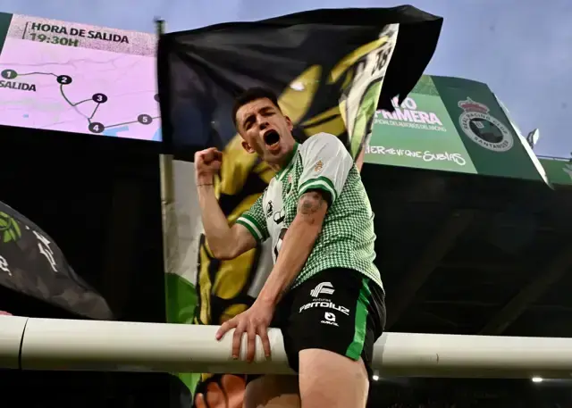 Un futbolista del Racing celebra el ascenso con una bandera verdiblanca mientras El Sardinero corea el regreso a Primera Divisi&oacute;n.